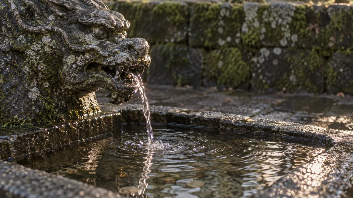 石の龍の口から細い水が落ち、下の水盤に受けられている