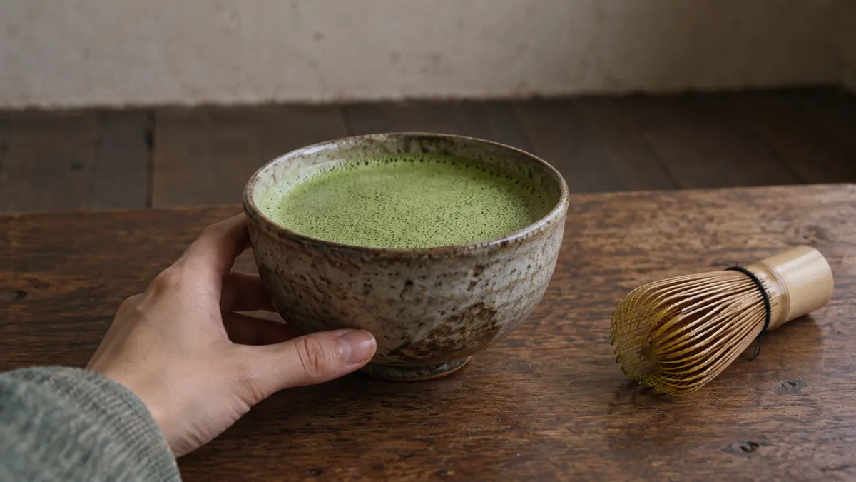 碗にたてられた抹茶を片手が持つ