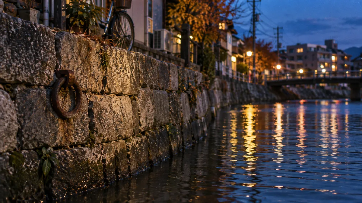 石積みの護岸に錆びた鉄の輪が残り、すぐ下を川の水が満たしている